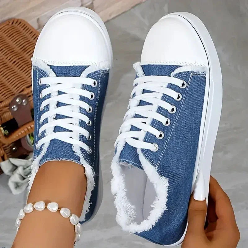 Blue denim sneakers with white rubber toe, frayed edges, and lace-up closure