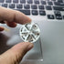 Hand holding a small white plastic wheel gear above a laptop keyboard