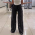 Woman wearing black wide-leg floral lace pants, high waist, relaxed fit, in modern store setting