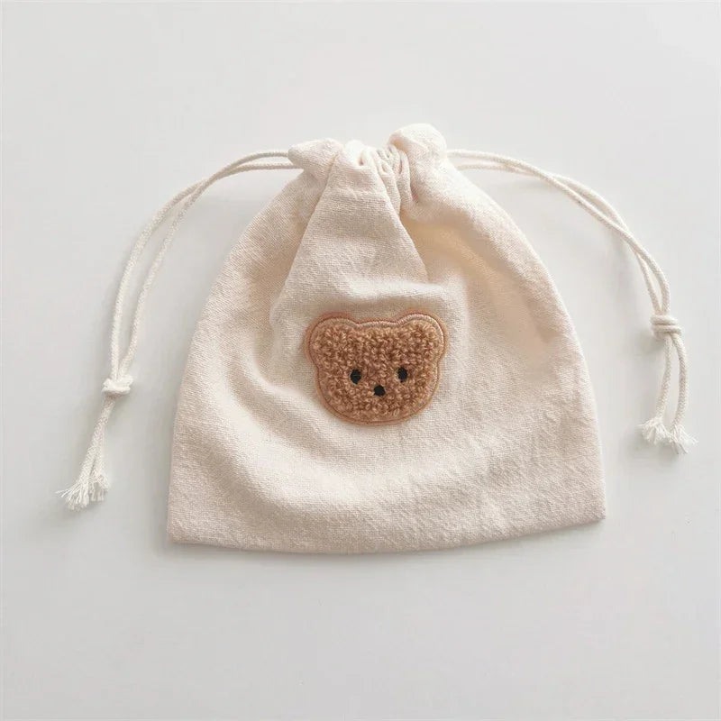 Beige cotton drawstring bag with cute teddy bear patch, soft material, relaxed fit