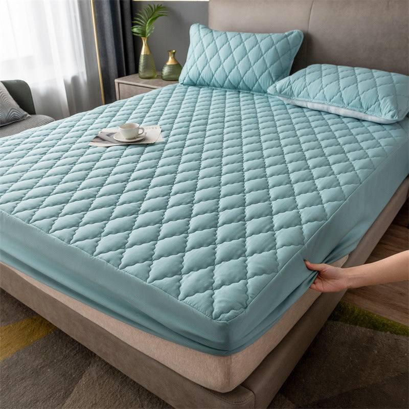 Light blue quilted fitted mattress cover with matching pillows in modern bedroom