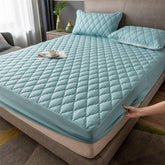 Light blue quilted fitted mattress cover with matching pillows in modern bedroom
