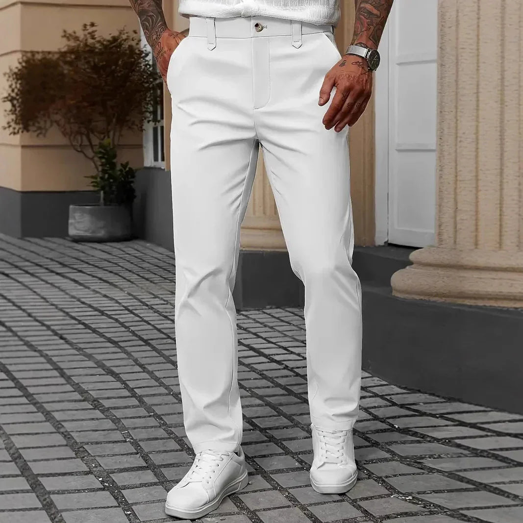 Men's slim fit white dress pants with pockets, paired with white sneakers, outdoor setting