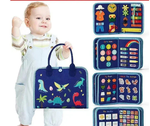 Toddler wearing light blue overalls and striped shirt, holding a navy blue dinosaur-printed educational felt activity book.