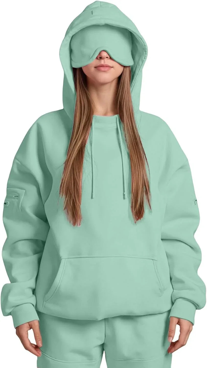 Woman wearing oversized mint green hoodie and sweatpants with matching eye mask, streetwear style