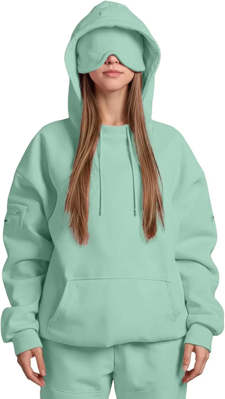 Woman wearing oversized mint green hoodie and sweatpants with matching eye mask, streetwear style