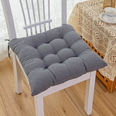 Plush grey tufted seat cushion on a white wooden chair, soft fabric, square shape, cozy fit.
