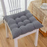 Plush grey tufted seat cushion on a white wooden chair, soft fabric, square shape, cozy fit.