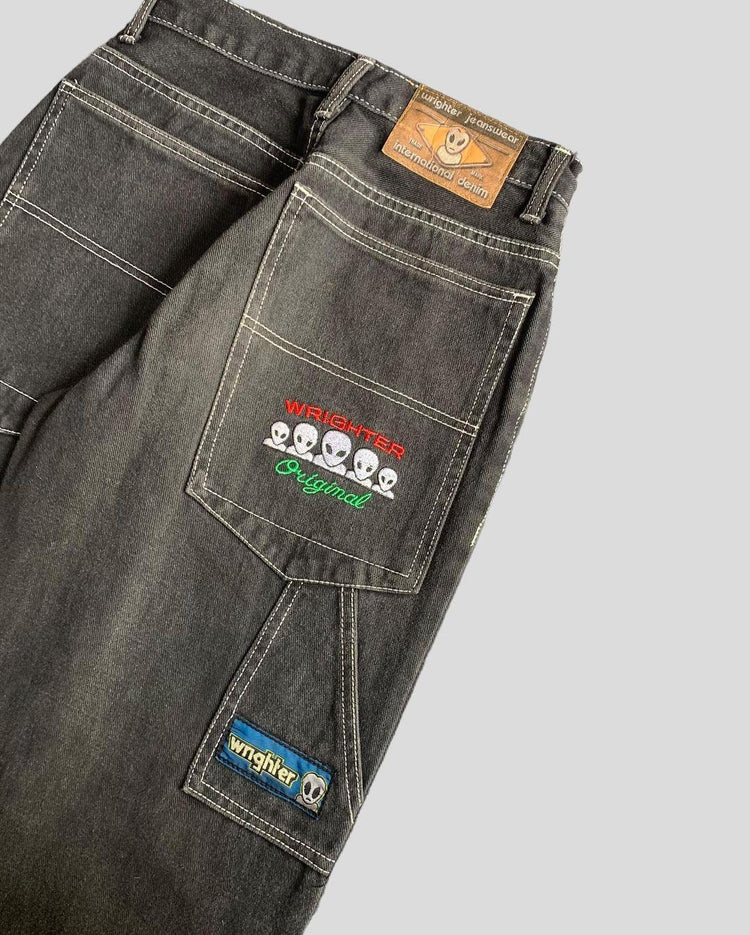 Black denim jeans with contrast stitching, embroidered alien graphics, and relaxed fit.