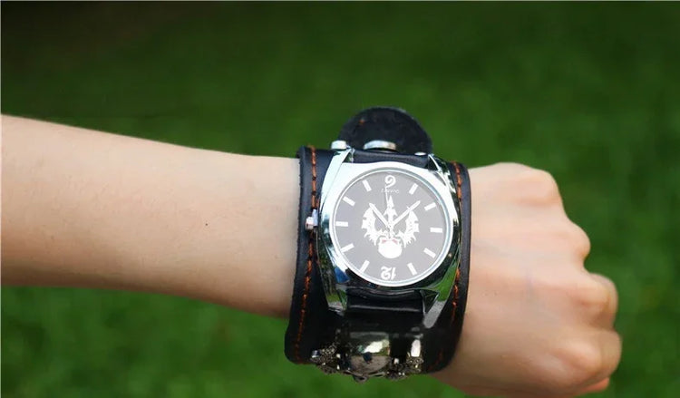 Black leather wide cuff wristwatch with bold face design, worn on wrist outdoors.
