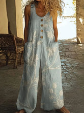 Light blue linen wide-leg jumpsuit with white floral print, sleeveless, relaxed fit, front buttons