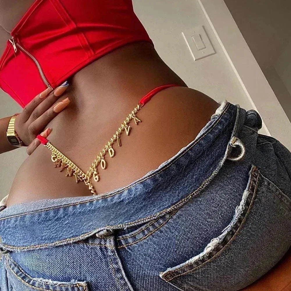 Red crop top with gold body chain, low-rise denim jeans, Y2K streetwear style.