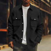 Man wearing black oversized button-up shirt jacket with chest pockets, white t-shirt, relaxed fit streetwear style