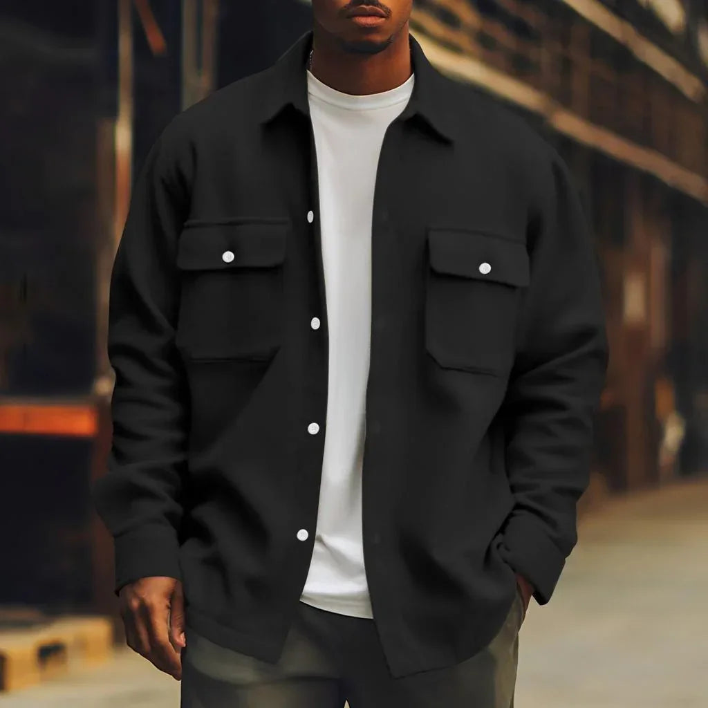 Man wearing black oversized button-up shirt jacket with chest pockets, white t-shirt, relaxed fit streetwear style