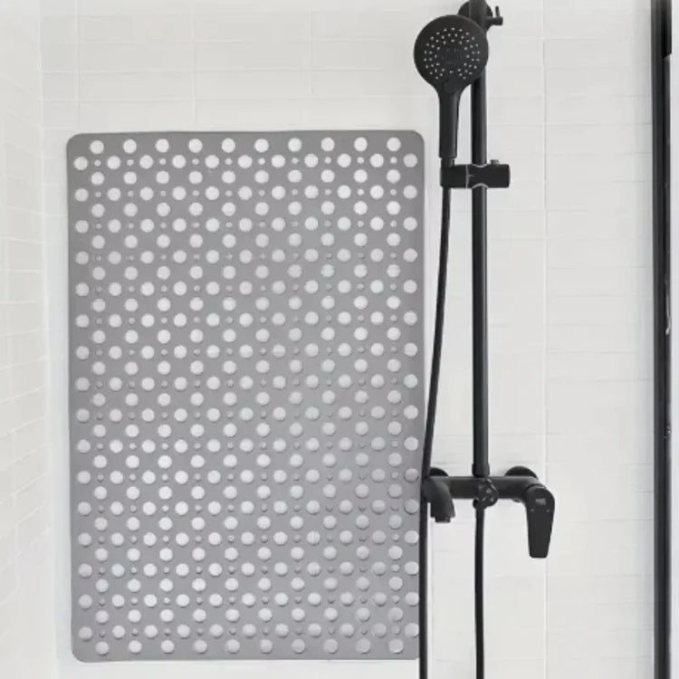 Gray non-slip rubber shower mat with circular holes on white tile, next to black shower head