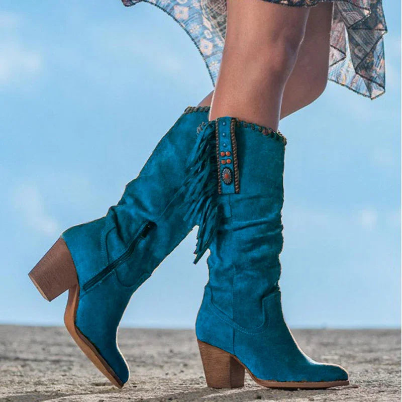 Woman wearing turquoise suede knee-high boots with fringe and wooden block heels