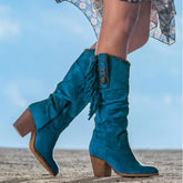 Woman wearing turquoise suede knee-high boots with fringe and wooden block heels