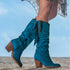 Woman wearing turquoise suede knee-high boots with fringe and wooden block heels