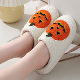 Cozy white fuzzy slippers with orange pumpkin design, plush material, relaxed fit