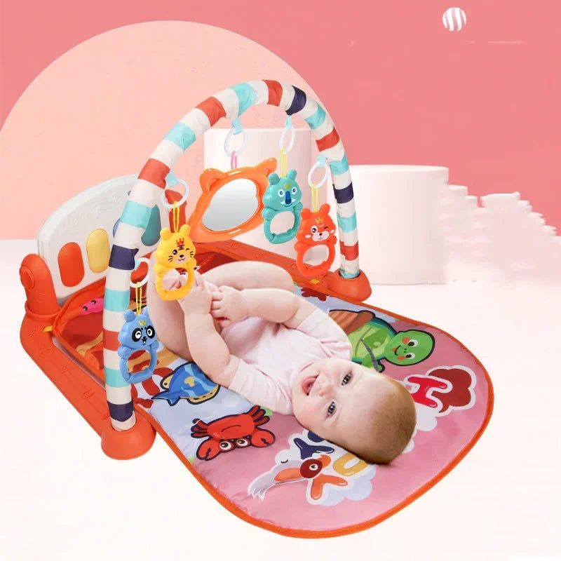 Baby in a pink short-sleeve bodysuit on a colorful play mat with animal prints and soft hanging toys