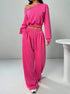 Woman wearing loose fit hot pink off-shoulder sweatshirt and wide-leg sweatpants set.