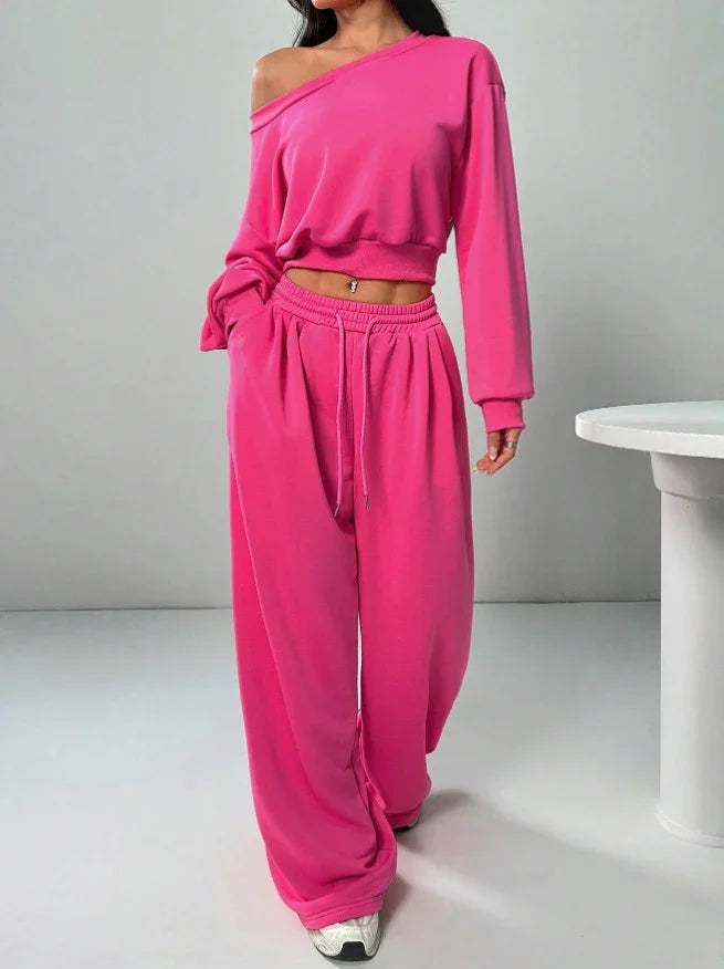 Woman wearing loose fit hot pink off-shoulder sweatshirt and wide-leg sweatpants set.