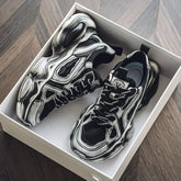 Chunky black and grey futuristic sneakers with bold details and thick soles in a shoebox