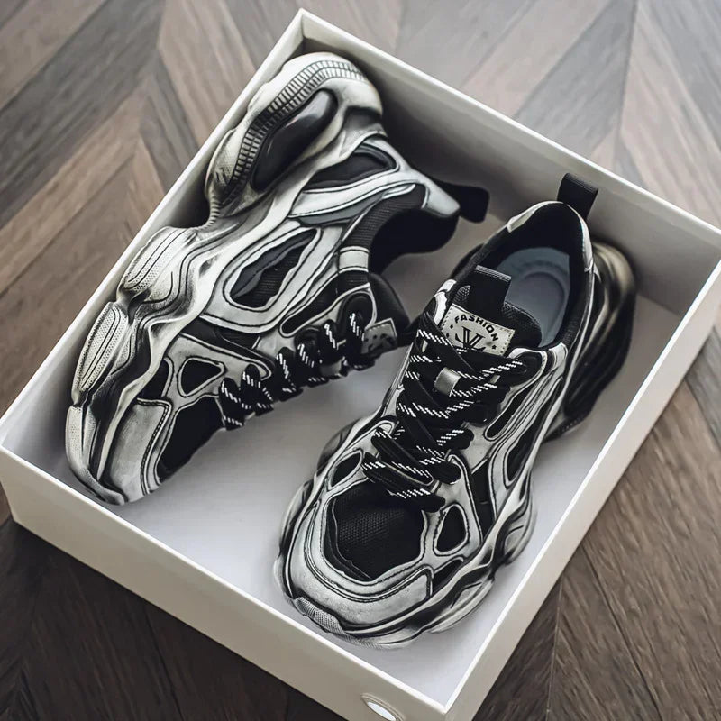 Chunky black and grey futuristic sneakers with bold details and thick soles in a shoebox