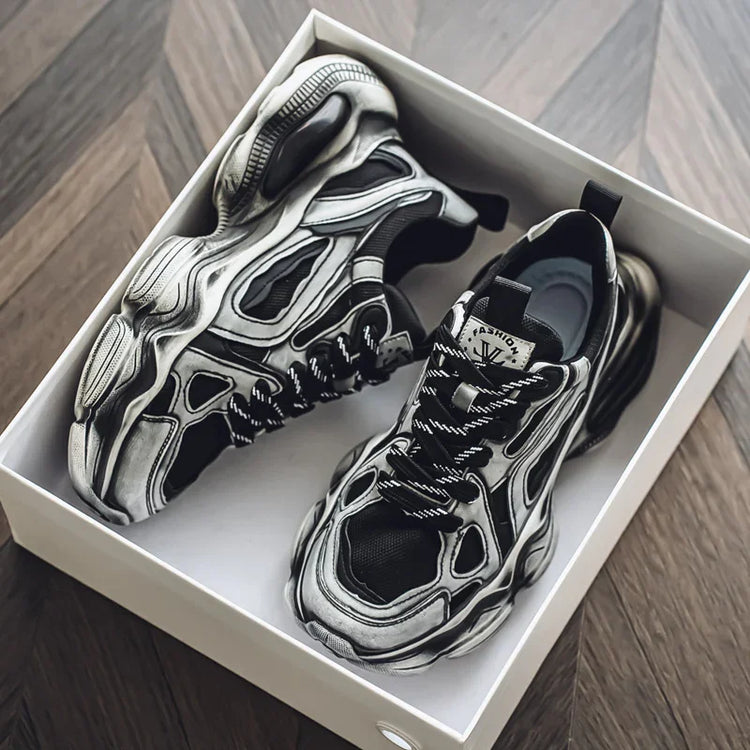 Chunky black and grey futuristic sneakers with bold details and thick soles in a shoebox