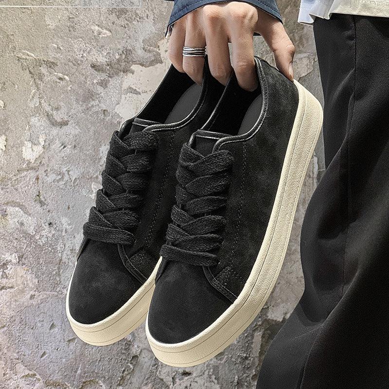 Black suede low-top sneakers with chunky white soles and wide laces, casual streetwear style