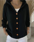 Woman wearing a black button-up hoodie with wooden buttons, white top and white pants