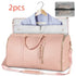 Pink duffel garment bag with gold zippers, shoulder strap, and matching mesh pouch, ideal for travel.