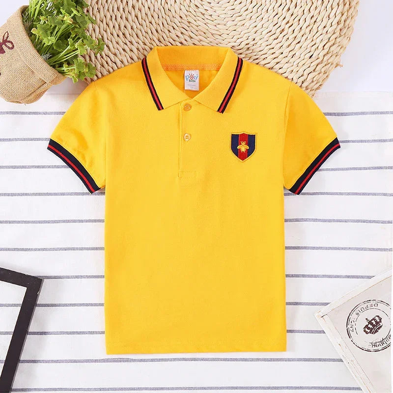 Yellow short sleeve polo shirt with collar, embroidered crest patch, and striped trim