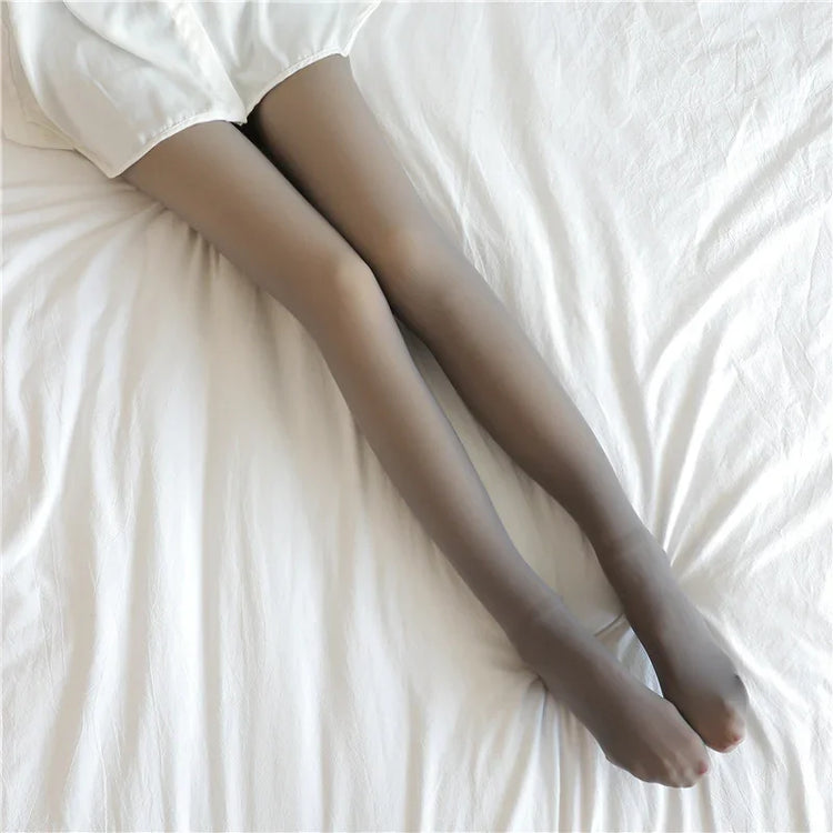 Sheer gray tights with a slim fit, worn with a white skirt, on a bed with white sheets.