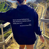 Woman outdoors in oversized black hoodie with positive quote, relaxed fit, walking on scenic trail