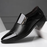 Black glossy formal shoe with perforated leather, side zipper, and sleek pointed toe.