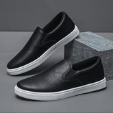 Black slip-on sneakers with white soles, faux leather material, minimalist streetwear style