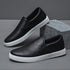 Black slip-on sneakers with white soles, faux leather material, minimalist streetwear style
