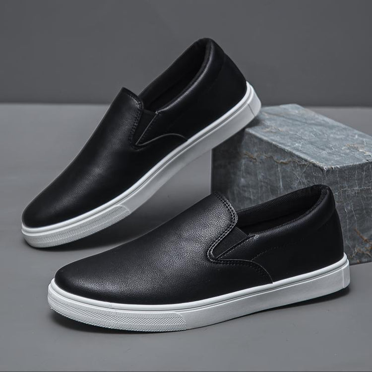 Black slip-on sneakers with white soles, faux leather material, minimalist streetwear style