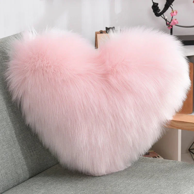 Fluffy pink heart-shaped faux fur pillow on a modern grey sofa, cozy home decor