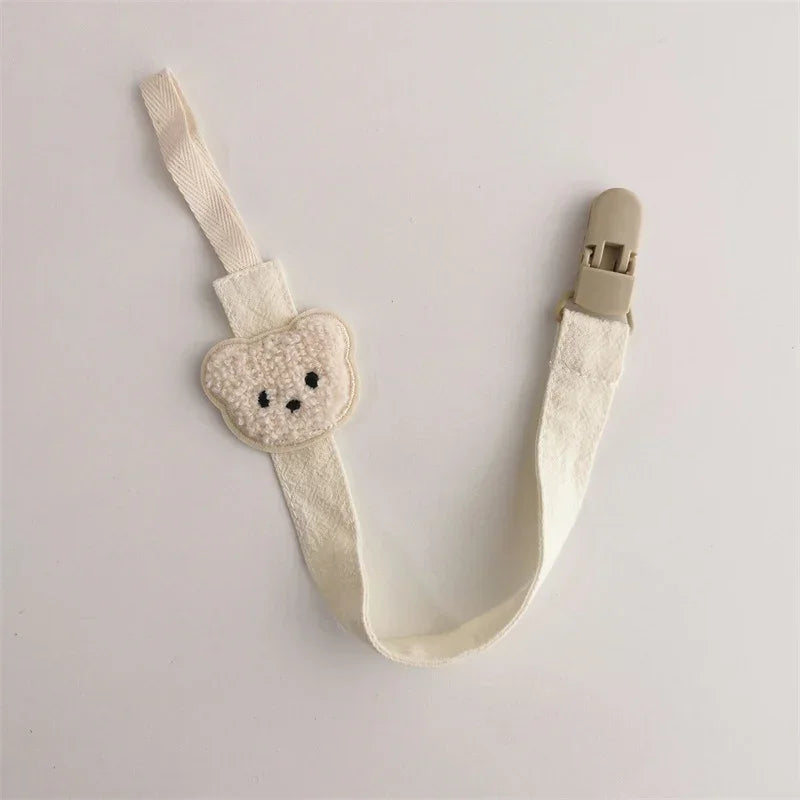 Cream fabric strap with bear face patch, metal clip, minimalist accessory style