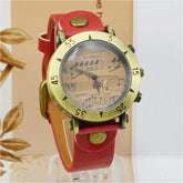 Vintage-inspired watch with red leather strap and musical note dial, bold brass accents.