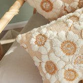 Textured throw pillow with cream and orange floral pattern on woven fabric