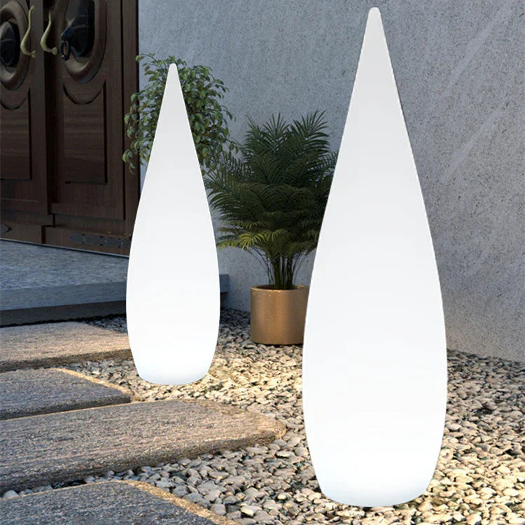 Modern outdoor space with two tall white cone-shaped LED floor lamps on stone path