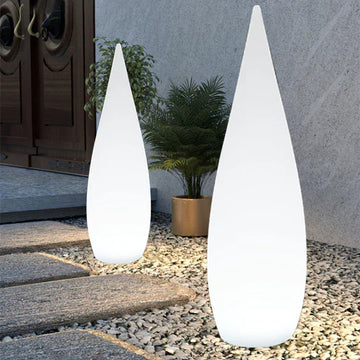 Modern outdoor space with two tall white cone-shaped LED floor lamps on stone path