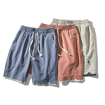 Three pairs of loose fit drawstring shorts in blue, pink, and beige with elastic waistbands.