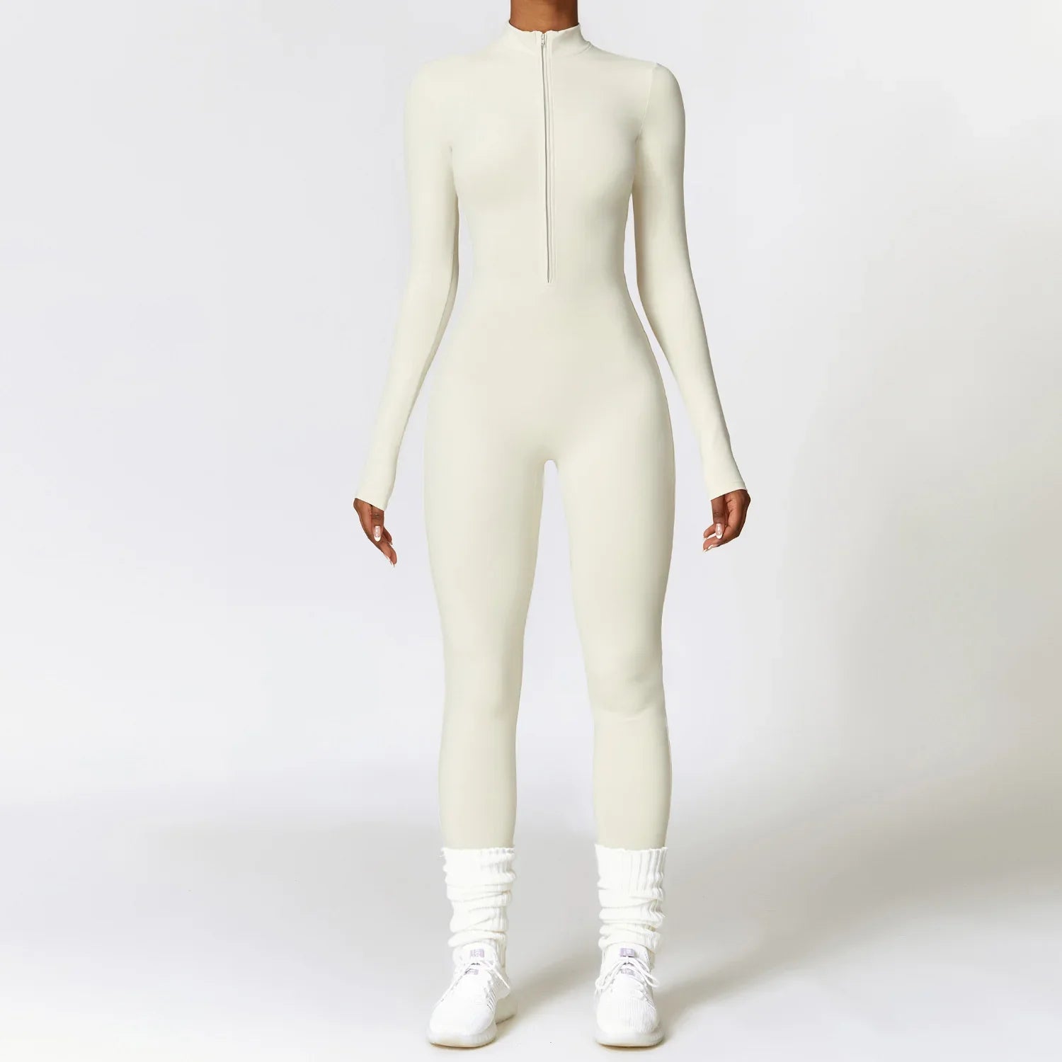 Woman wearing a fitted long sleeve white jumpsuit with front zipper, sporty streetwear style.