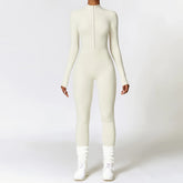 Woman wearing a fitted long sleeve white jumpsuit with front zipper, sporty streetwear style.