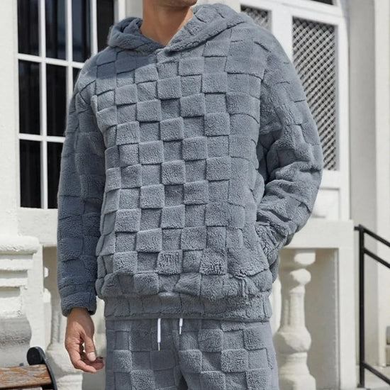 Man wearing a grey textured fleece hoodie and pants set with a checkered pattern, relaxed fit