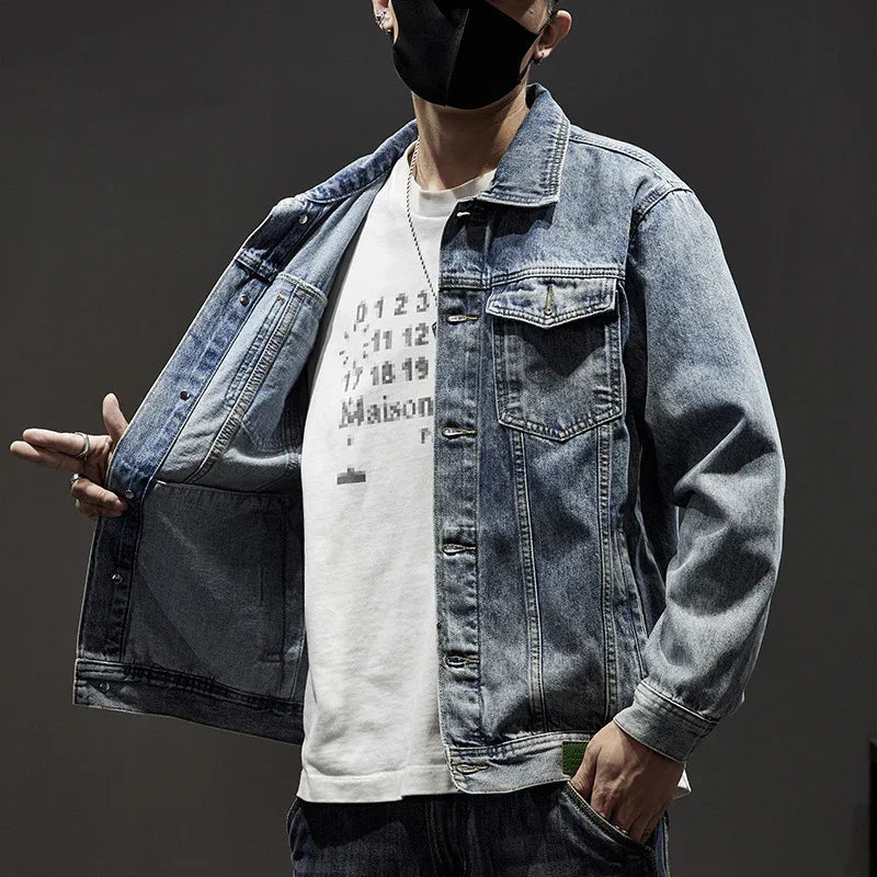 Man wearing relaxed-fit blue denim jacket over a white graphic t-shirt, urban streetwear style